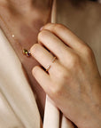 A person wearing an open rose gold diamond cuff ring on their finger and a pendant necklace.
