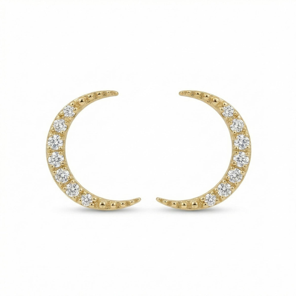 A pair of gold crescent moon stud earrings featuring pave-set round diamonds lie symmetrically against a plain white background.