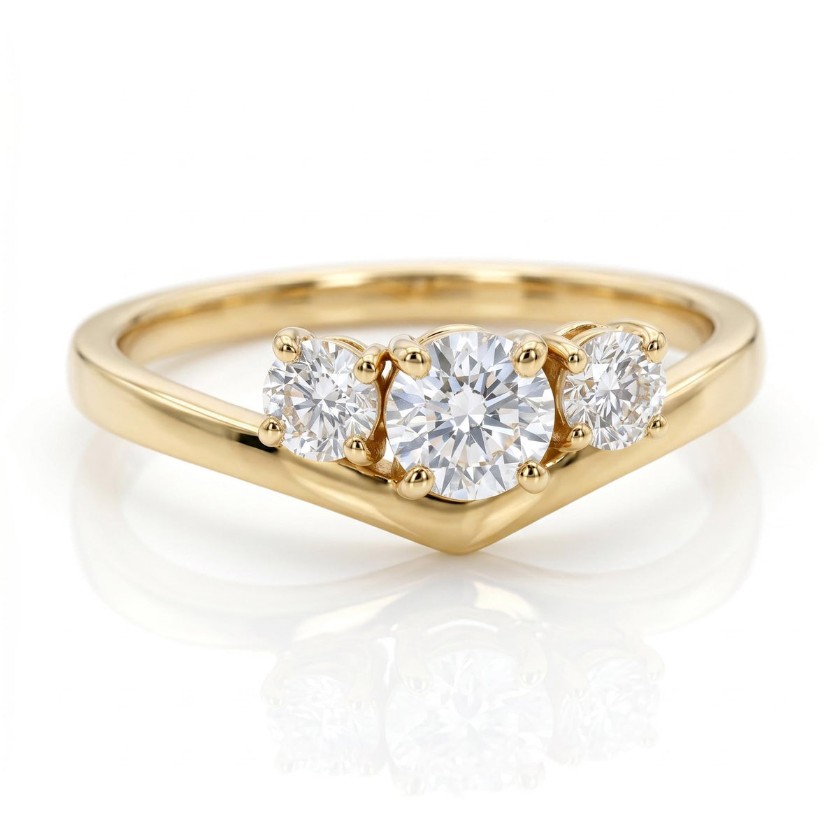 A yellow gold three-stone ring with a V-shaped chevron band rests on a white surface, displaying a large center diamond and two smaller side diamonds.