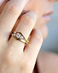 Side-angled view of the gold ring with three sparkling round diamonds on a finger.
