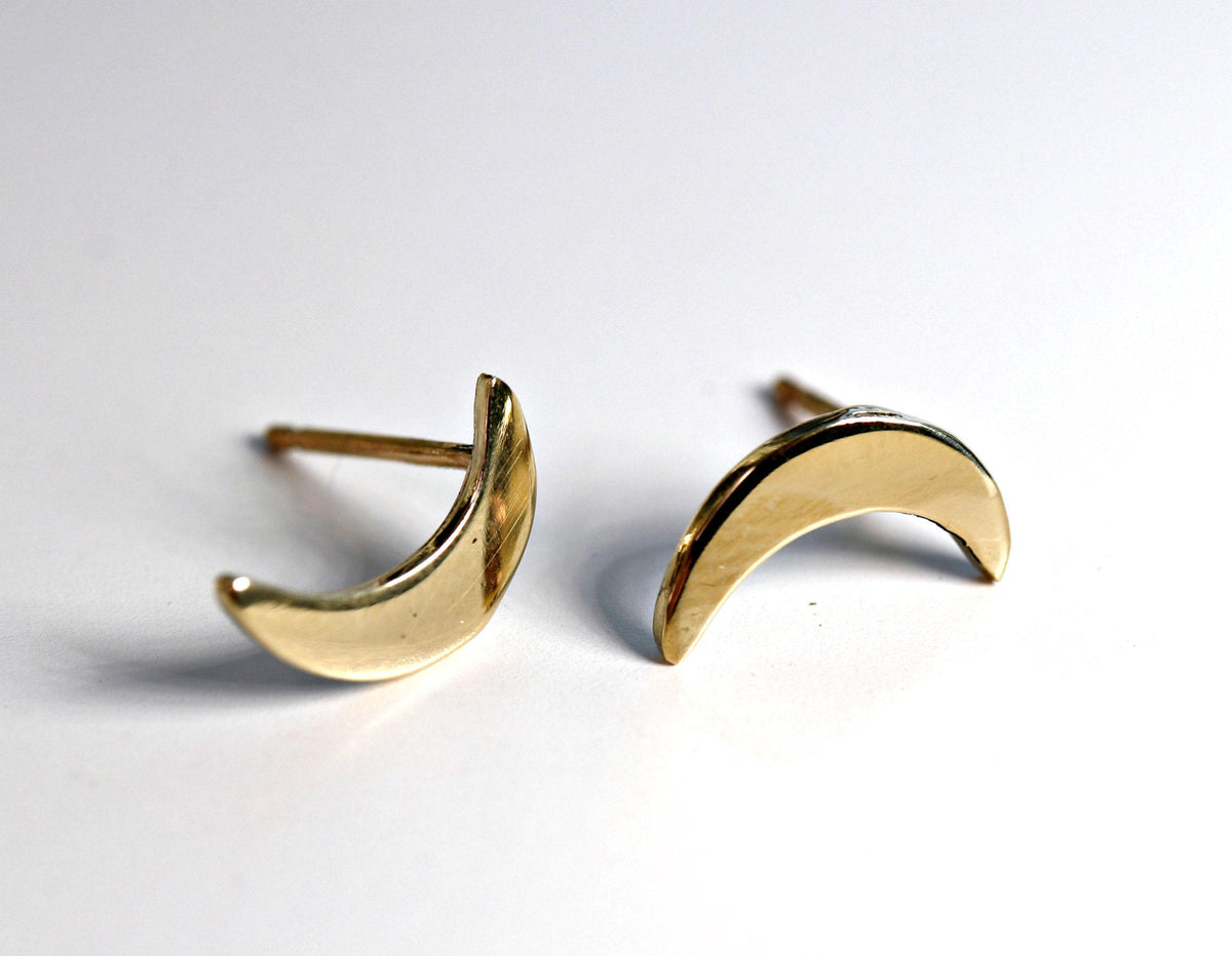 Two smooth polished gold crescent moon stud earrings with posts visible against a white background.