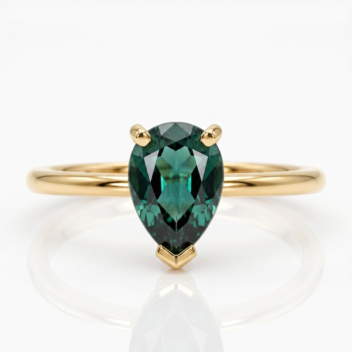 Front view of a gold ring featuring a prong-set pear-cut dark green gemstone on a white surface.