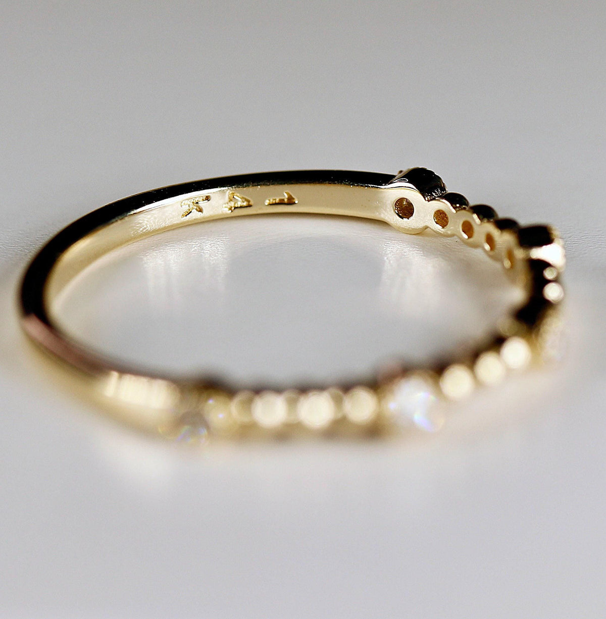 Close-up of the underside of a gold ring resting on a white surface, showing the 14k stamp inside the band.