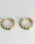 Top-down view of two gold hoop earrings displaying the inner clasp mechanism and green gemstone channel setting.
