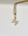 A gold chain necklace rests on a white surface, showcasing a Pisces zodiac pendant encrusted with small diamonds.