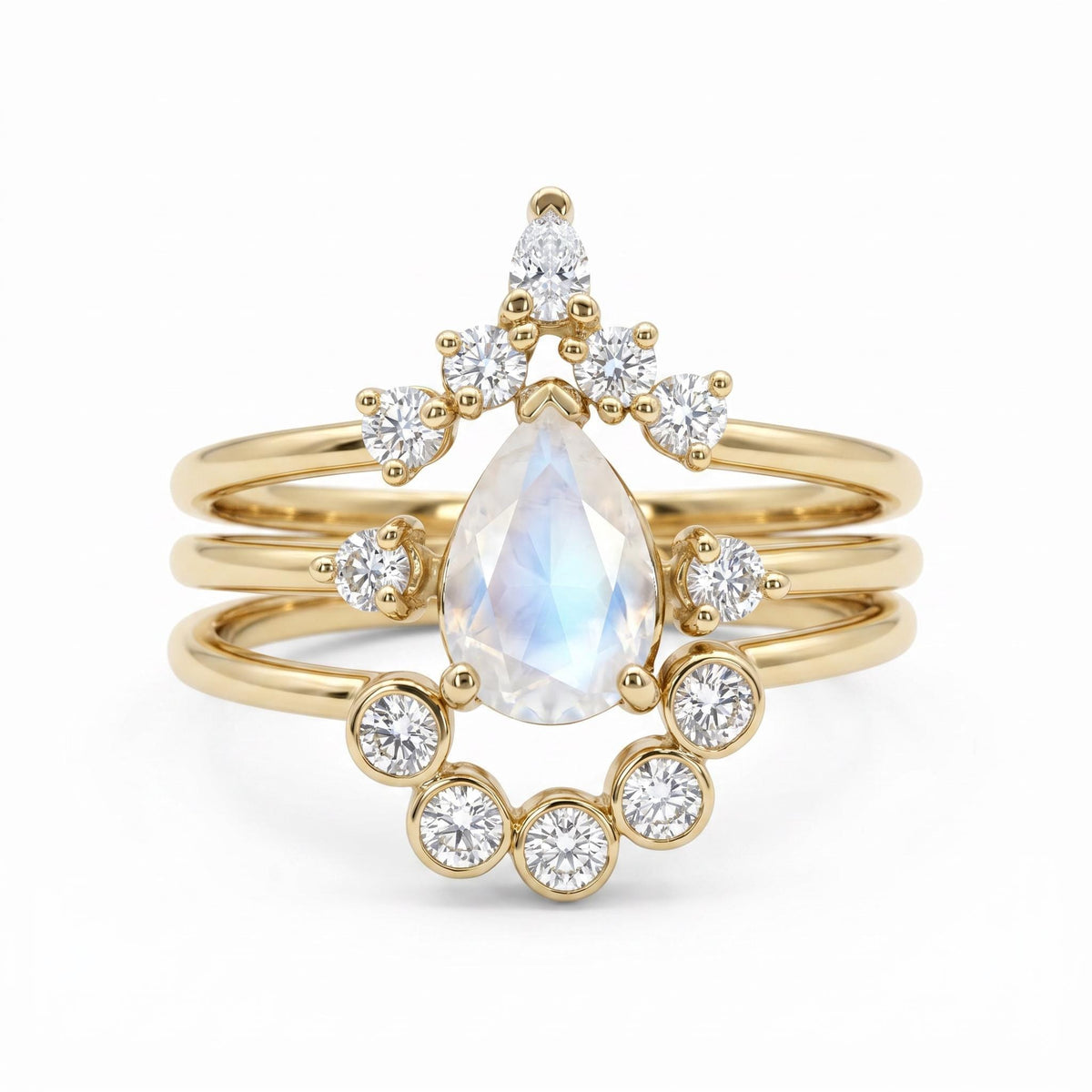 A stack of three gold rings featuring a pear-shaped moonstone center stone and multiple small round diamonds.