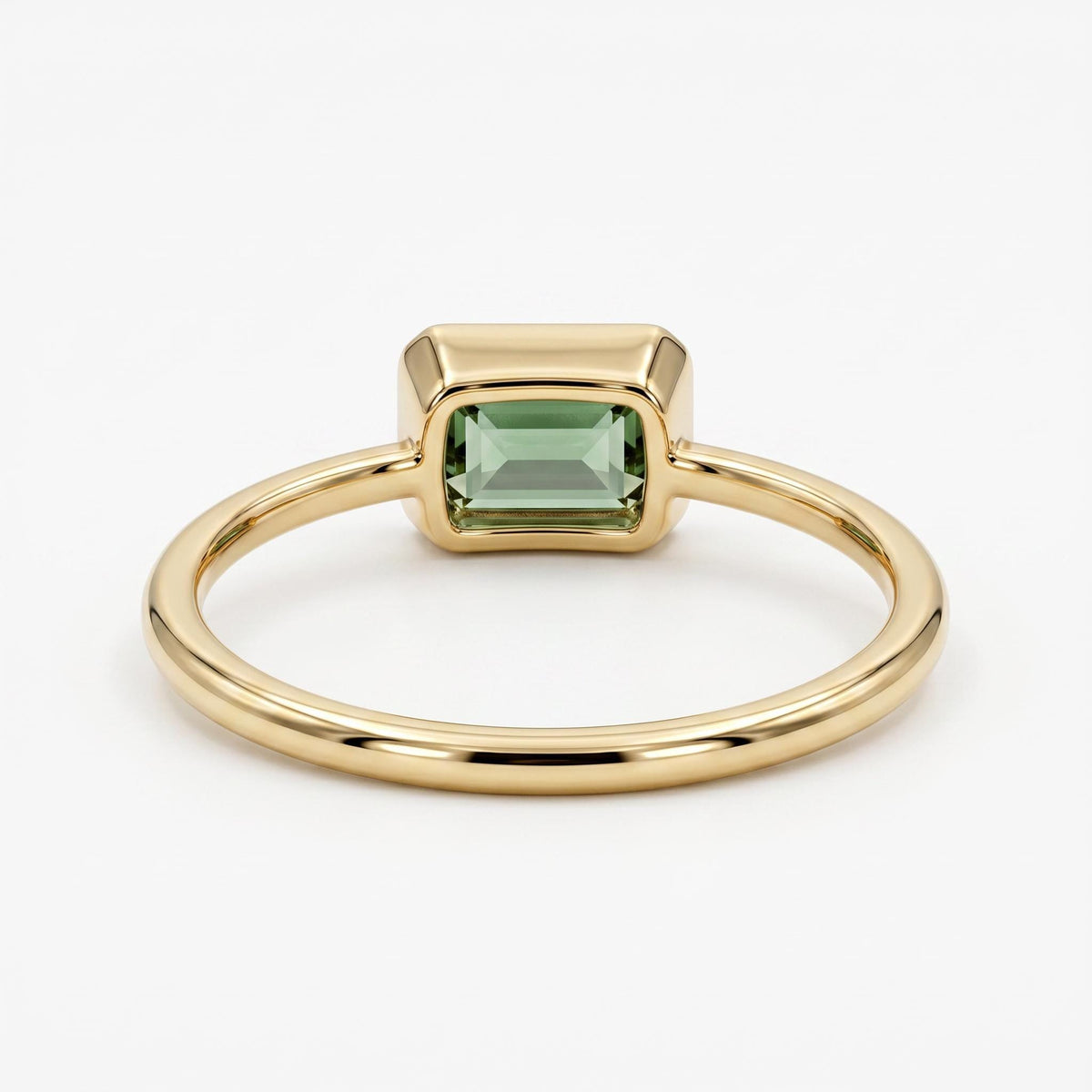 Rear view of a gold ring showing the bezel setting holding a green emerald-cut gemstone.