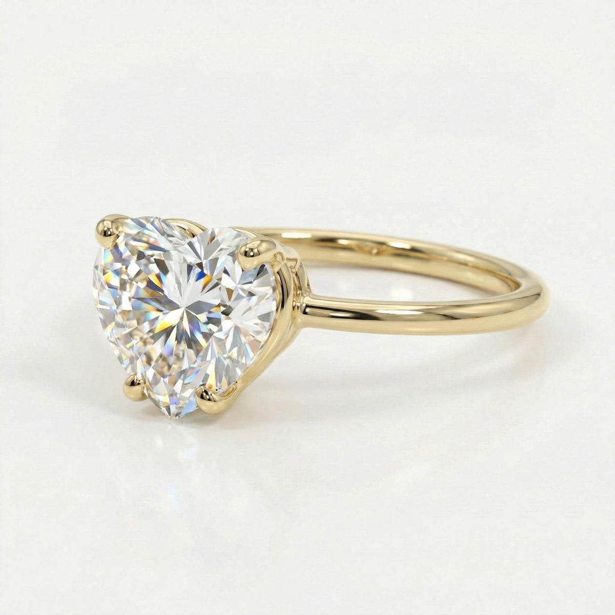 A gold solitaire ring with a large heart-cut gemstone sitting on a light surface.
