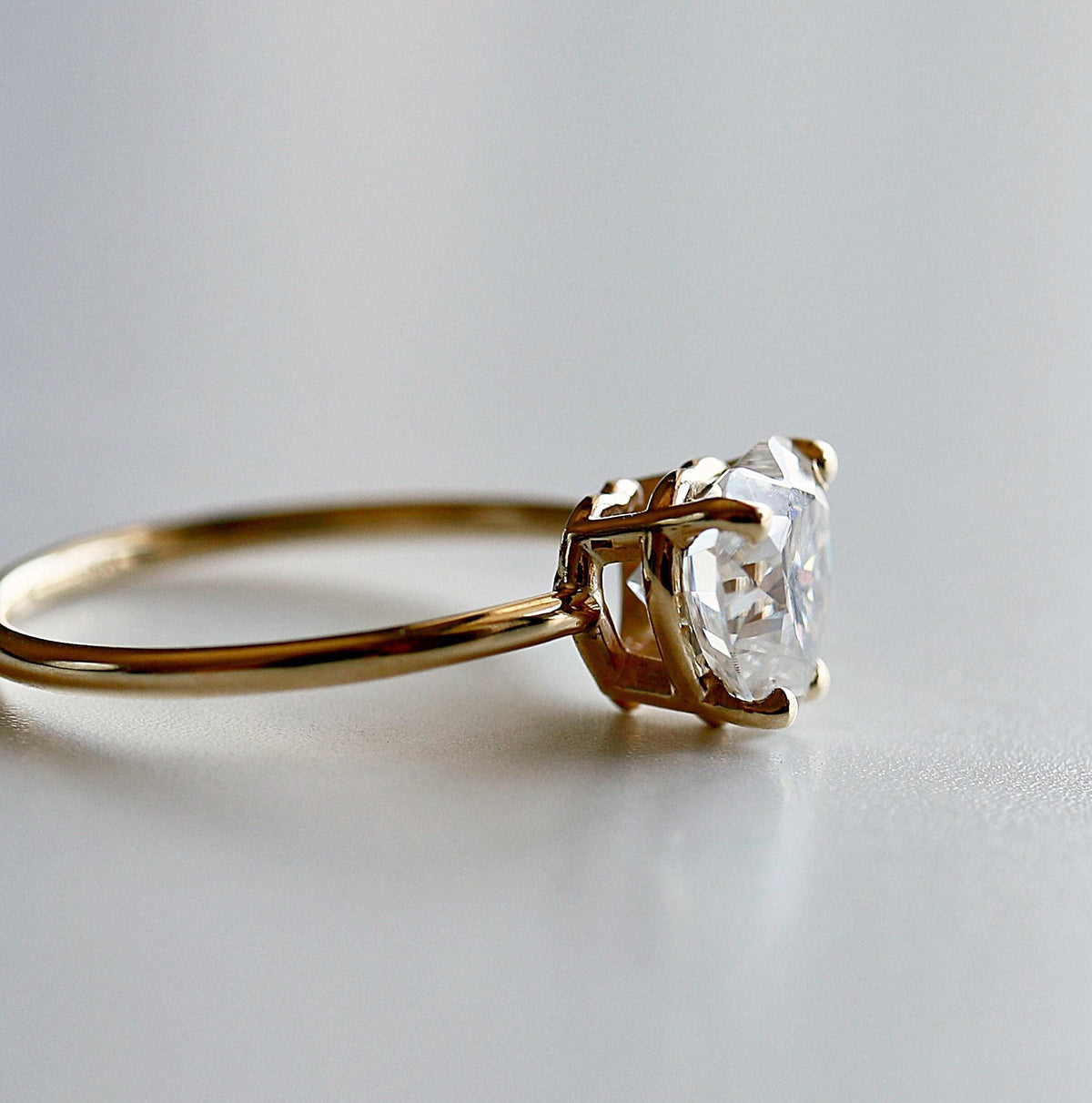Profile view of the thin gold band and the prongs securing the heart-shaped stone.