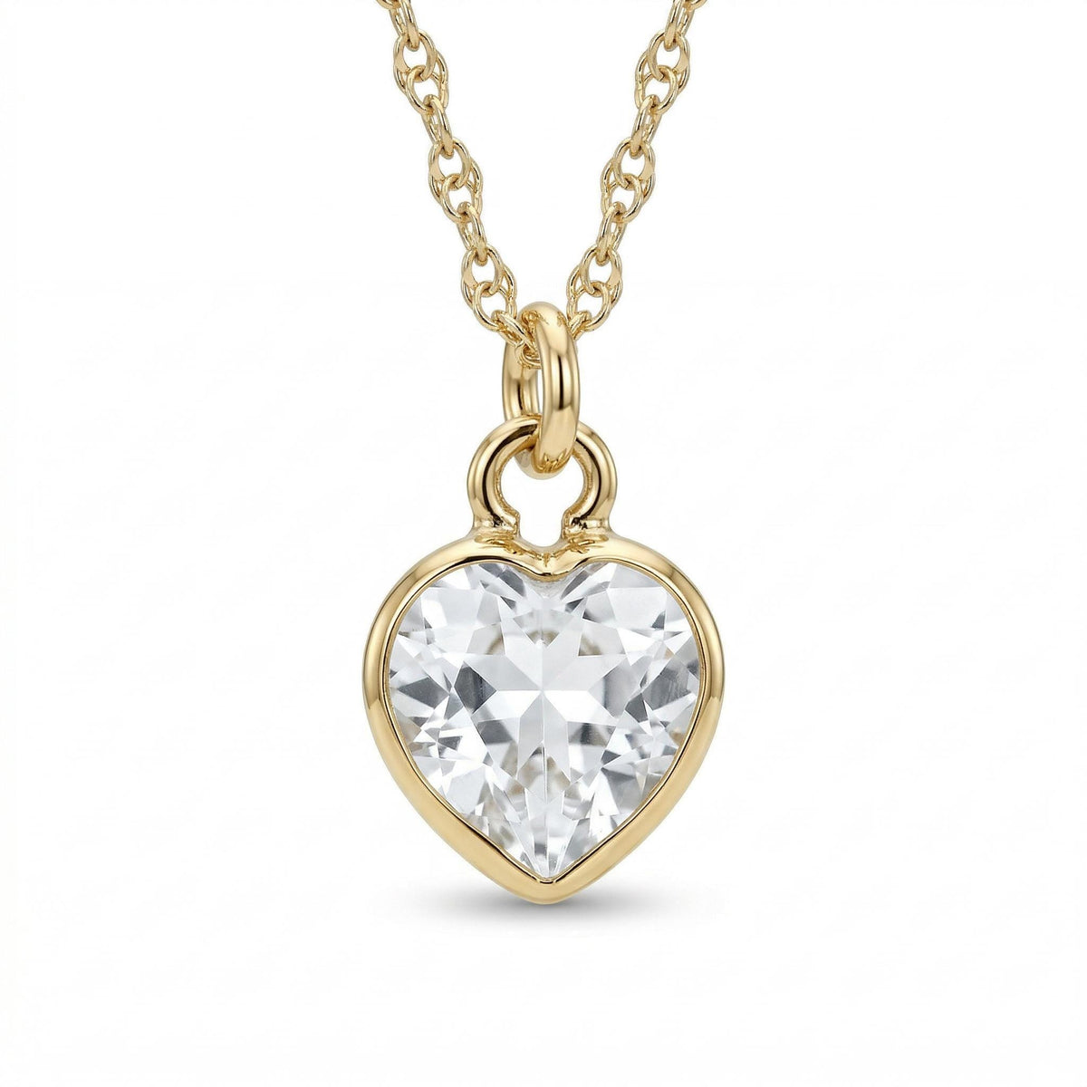 Close up of a gold necklace featuring a faceted heart-shaped clear gemstone pendant hanging from a delicate chain.