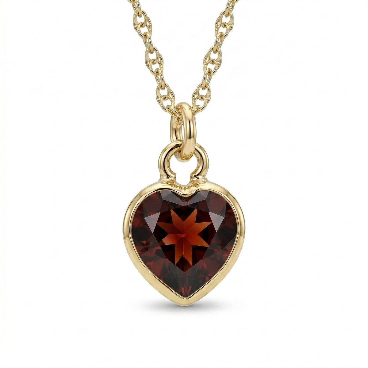 A gold chain necklace holds a faceted heart-shaped dark red gemstone pendant.